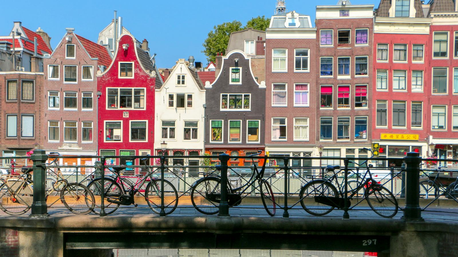 Bicikli na mostu preko kanala i tipične kuće u Amsterdamu