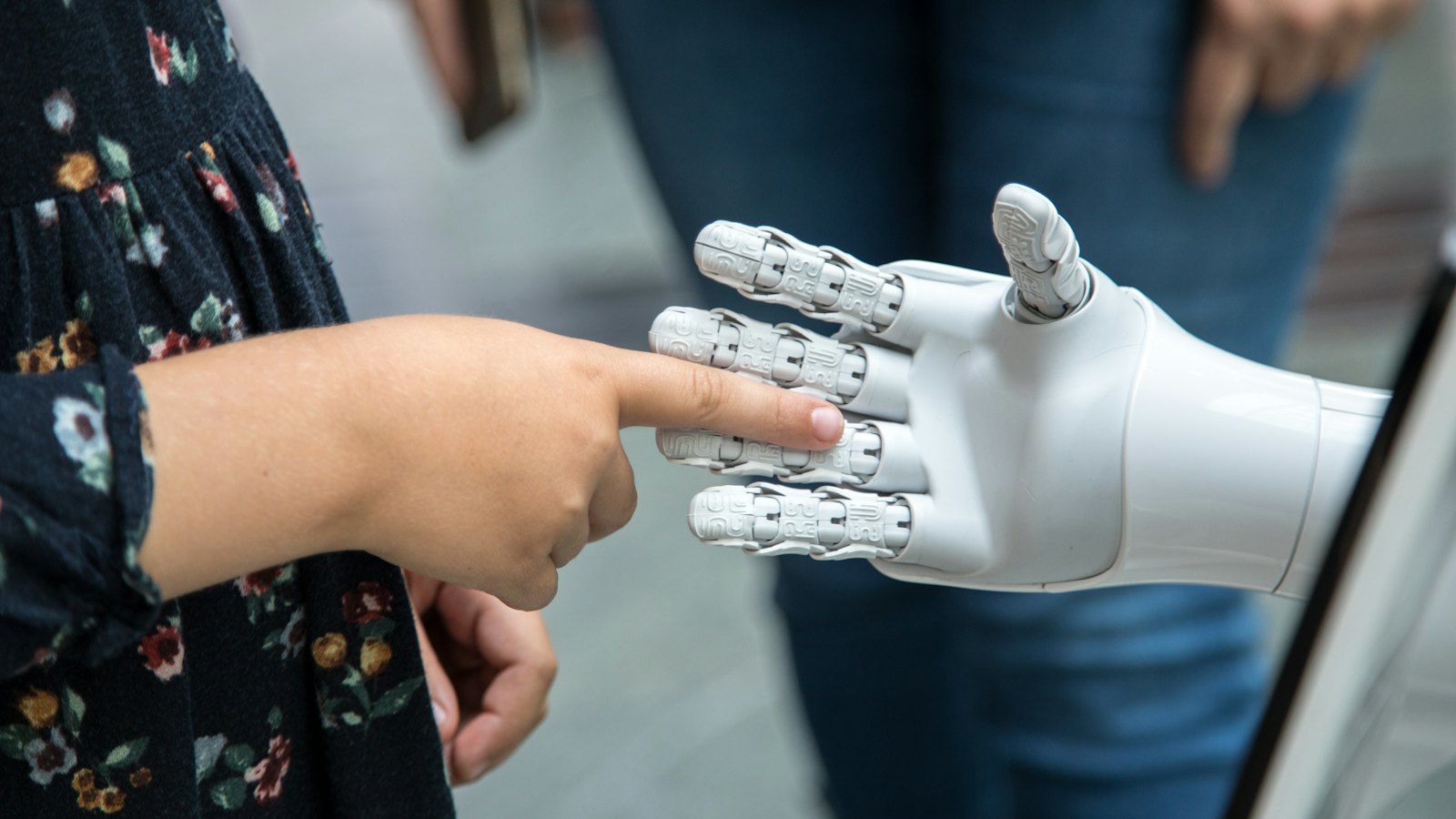 Dete prstom dodiruje belu robotsku ruku