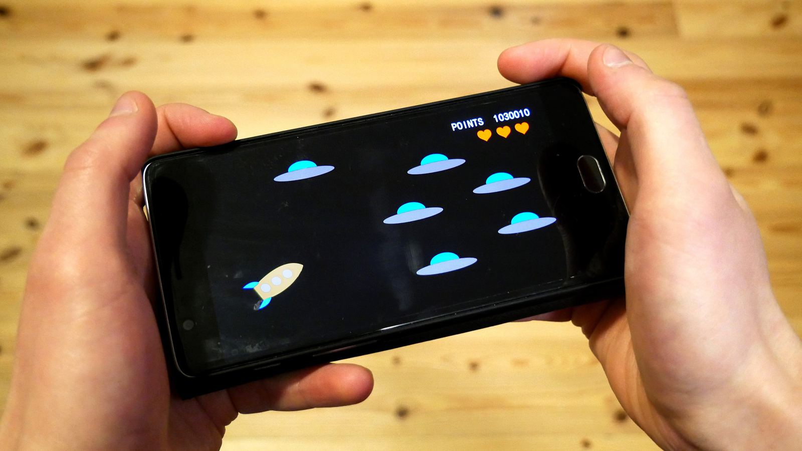 Ruke drže telefon sa igricom