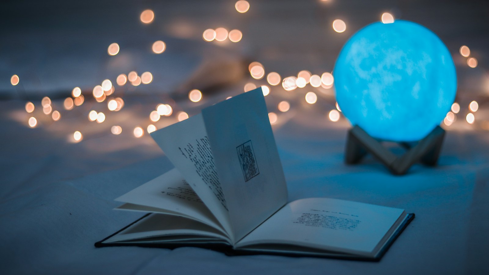 Otvorena knjiga pored lampe u obliku Meseca