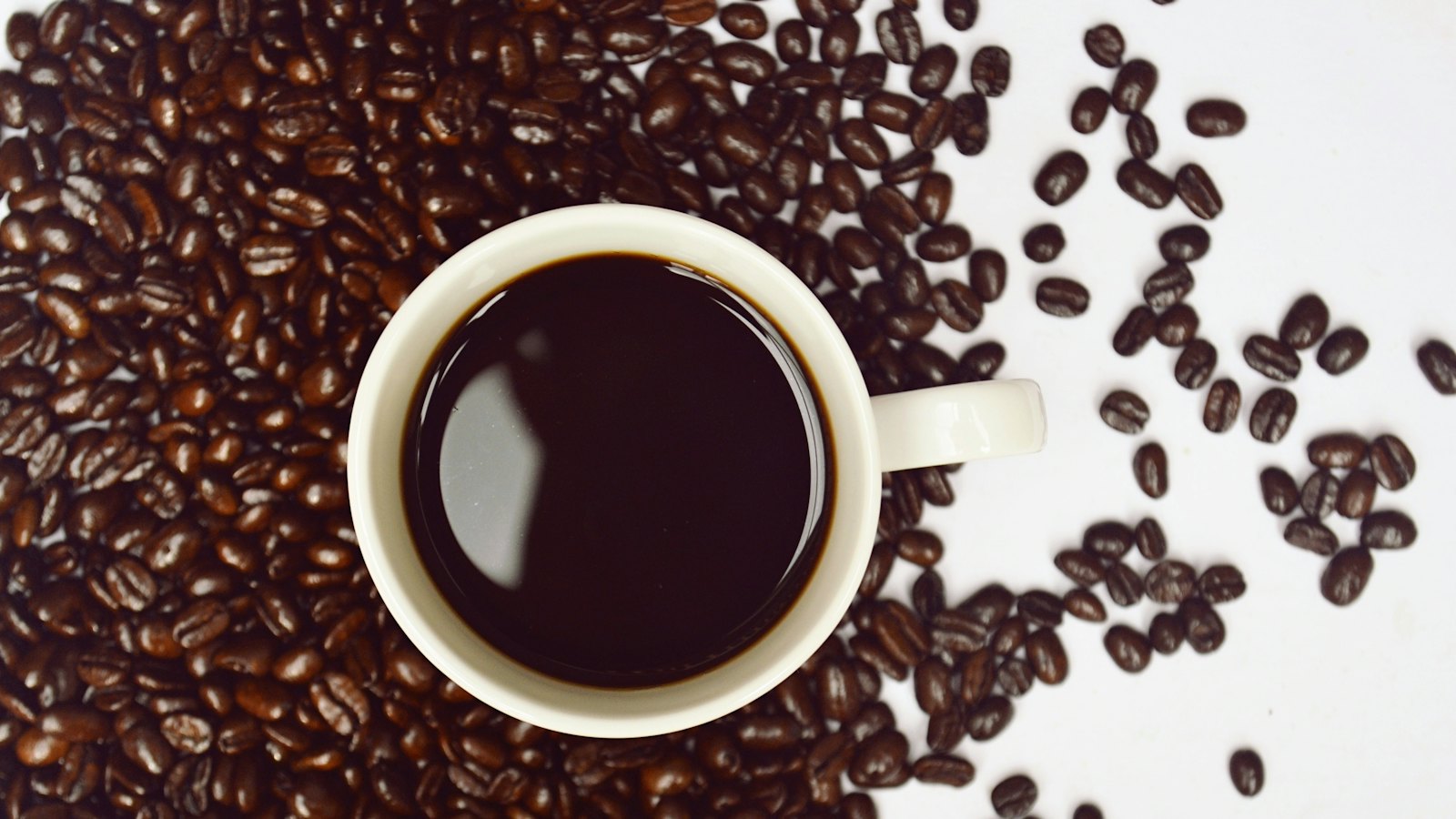 Šoljica kafe okružena zrnima kafe